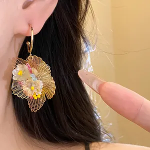 Nahaufnahme goldener filigraner Blumenohrringe mit bunten Perlen und floralen Akzenten