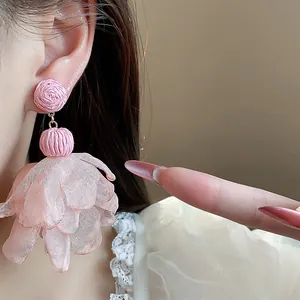 Close-up of elegant pink raffia and chiffon flower drop earrings worn by a model