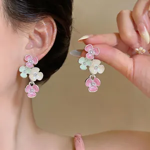 Detailed view of elegant pastel floral drop earrings with rhinestones worn by a model