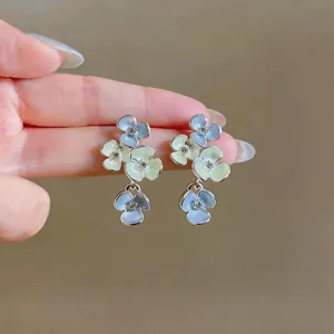 Detailed view of floral drop earrings with blue and yellow enamel flowers and small crystals