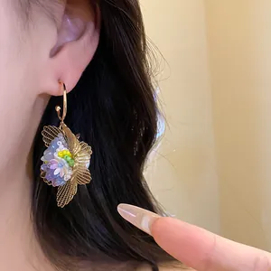 Nahaufnahme eleganter floraler Creolen mit bunten Perlen und goldener Mesh-Blüte