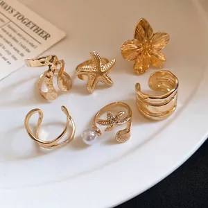 Détail d'un ensemble de six bagues vintage dorées avec des motifs d'étoiles de mer et fleurs