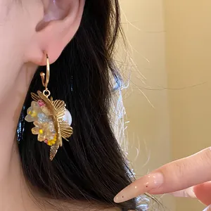 Detaillierte Nahaufnahme von goldenen Vintage-Ohrhängern mit hohlen Blumen und Perlen