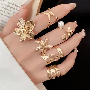 Gros plan d'un ensemble de 6 bagues dorées vintage avec motifs de fleurs et d'étoiles de mer