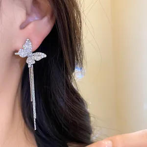 Stunning detail of elegant sparkling butterfly tassel earrings worn on a model's ear