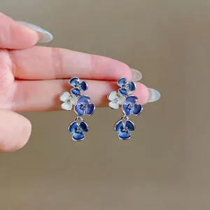 Detailed view of elegant blue and white floral stud earrings with sparkling rhinestone accents.