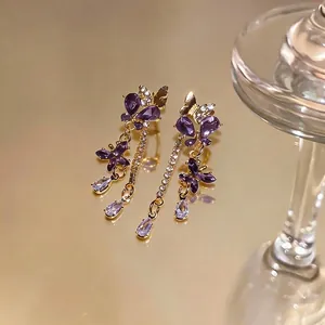 Eleganti orecchini a farfalla dorati con cristalli viola e diamanti scintillanti.