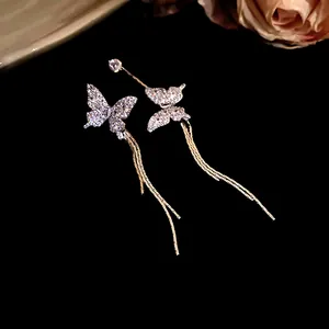 Detailed view of sparkling asymmetric butterfly tassel earrings with pavé crystals.