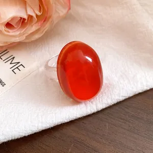 Close-up of vintage oval red resin ring with a transparent band on white cloth
