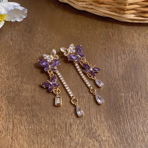 Orecchini vintage a farfalla con cristalli viola e strass scintillanti su legno