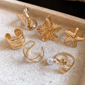 Gros plan d'un ensemble de 6 bagues vintage dorees avec etoile de mer et perles