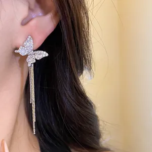 Close-up of elegant silver butterfly tassel earrings with sparkly rhinestones on model
