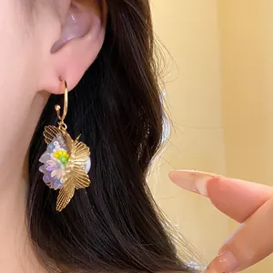 Detailaufnahme eines Vintage-Ohrhängers mit hohler Blume und Schmetterlingsflügel