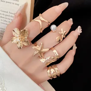 Gros plan d'un ensemble de bagues dorées vintage avec perles, fleurs et étoiles de mer.