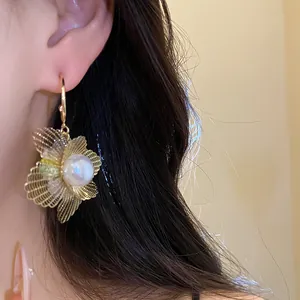 Nahaufnahme eines eleganten Hohlblumen-Ohrrings mit Perlenzentrum am Ohr eines Models