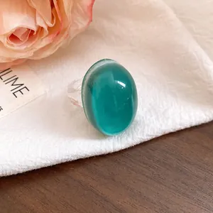 Close-up of a vintage oval resin ring with a turquoise translucent top and clear band.