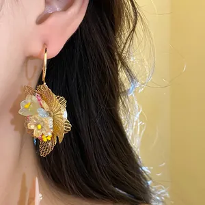 Detail der goldenen Netzblumen-Ohrringe mit bunten Perlen im eleganten Vintage-Stil.