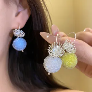 Close-up of elegant crystal flower earrings with textured colorful spherical dangles