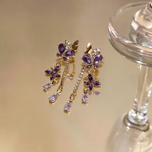 Vista macro dettagliata di orecchini a farfalla viola con strass scintillanti e placcatura in oro giallo