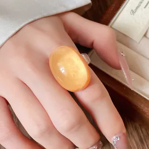 Detailed close-up of a vintage orange oval resin ring worn on a woman's index finger
