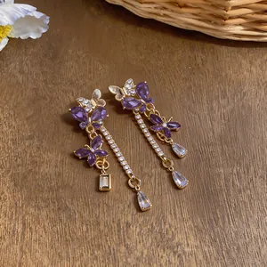 Primo piano di orecchini vintage a farfalla con cristalli viola e nappe dorate