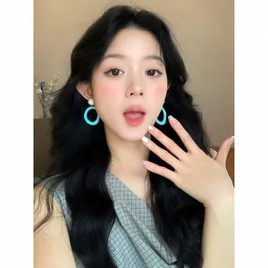 Vibrant turquoise dopamine style hoop earrings worn by a model for a summer look