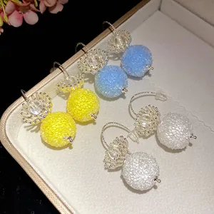 Detailed close-up of crystal beaded ball earrings in yellow, blue and white colors