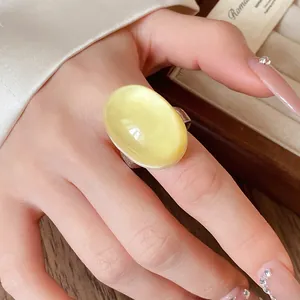 Detailed close-up of a vintage light yellow oval resin ring worn on the index finger.