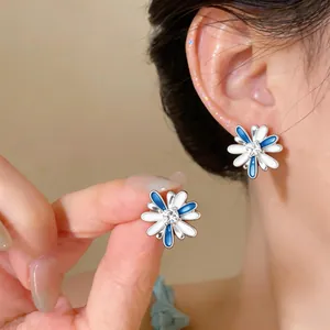 Detail view of blue and white enamel flower stud earrings with a central zircon