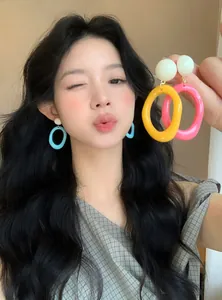 Bright dopamine-style colorful resin hoop earrings worn by a model for a summer look