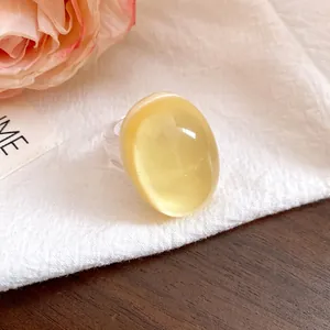 Detailed view of a vintage yellow oval resin ring with a transparent band on white cloth.