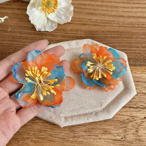 Close-up of vibrant blue and orange chiffon flower earrings with yellow stamen details.