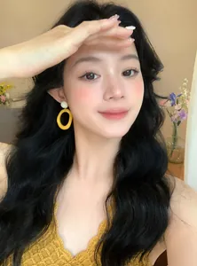 Close-up portrait of an Asian model wearing large yellow dopamine resin hoop earrings