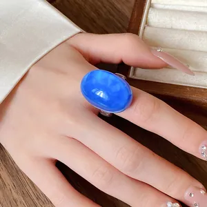 Close-up of a vintage blue oval resin ring worn on a finger as a fashion statement
