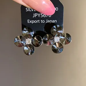 Macro detail of smoky grey crystal flower stud earrings with clear central zircon stone