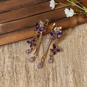 Dettaglio ravvicinato di orecchini a farfalla viola con nappe e cristalli vintage raffinati.
