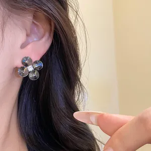 Close-up of elegant flower stud earrings with dark faceted petals and central zircon
