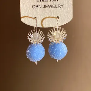 Close-up of blue beaded drop earrings with crystal flower accent on display card