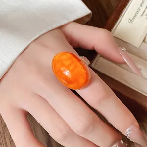 Close-up detail of a vintage orange oval resin ring featuring a marbled texture