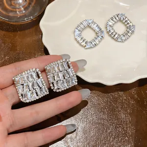 Macro detail of sparkling square zircon earrings with silver needle posts