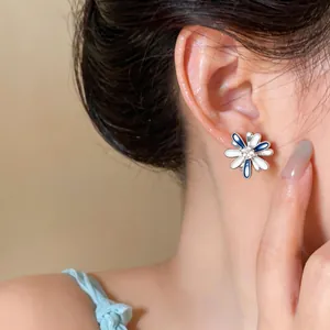 Detailed close-up of blue and white flower stud earrings with zircon on an Asian model