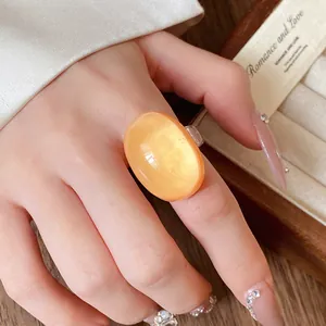 Elegant close-up view of a vintage orange oval resin ring on a hand with luxury nails.