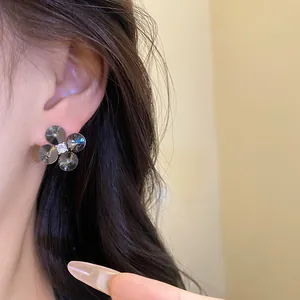 Detailed view of elegant silver flower stud earrings with zircons worn by a model