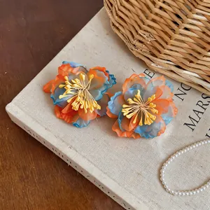 Close-up of vibrant chiffon flower earrings with orange and blue gradient petals