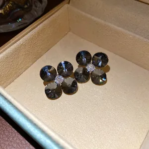 Close-up of elegant flower stud earrings with dark grey crystals in a jewelry box.
