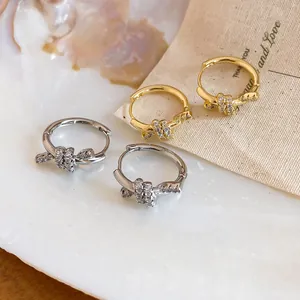 Detailed macro shot of 14k gold-plated knot huggie earrings with sparkling zircons