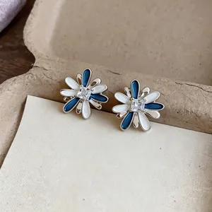 Close-up detail of stylish flower stud earrings with blue white enamel and zircon center