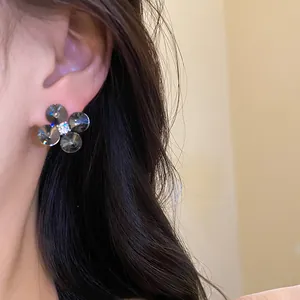 Close-up of elegant flower stud earrings with dark grey zircons on ear