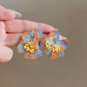 Close-up detail of blue and orange chiffon flower earrings with yellow stamens