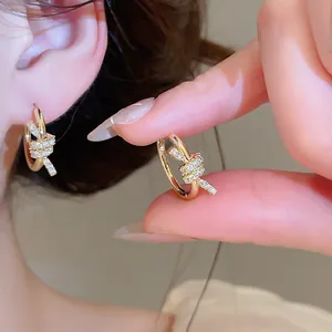 Detailed macro view of 14k gold plated knotted hoop earrings with sparkling zirconia accents.